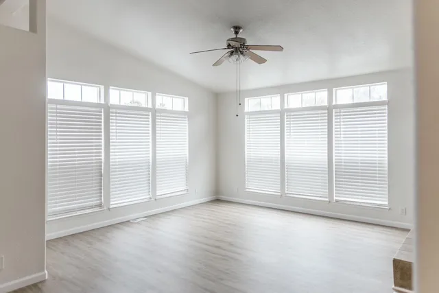 an empty room with windows and fireplace
