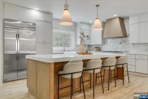 a kitchen with stainless steel appliances granite countertop a sink a stove a refrigerator and island with wooden floor