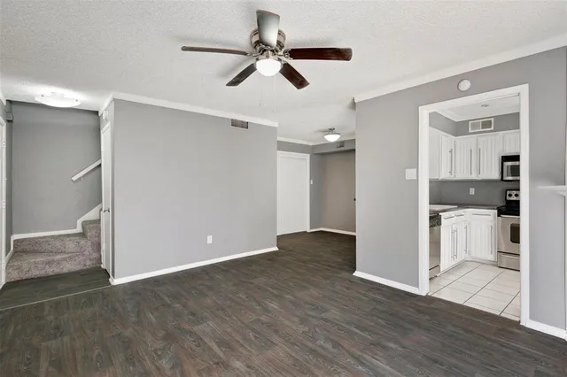 a view of empty room with wooden floor and ceiling fan