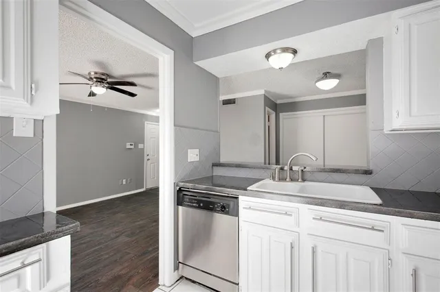 a kitchen with granite countertop a sink cabinets and stainless steel appliances