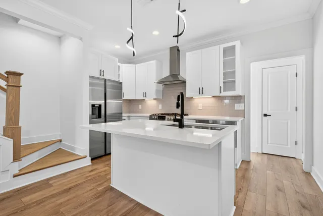 a kitchen with stainless steel appliances granite countertop a sink a stove a refrigerator and island with wooden floor