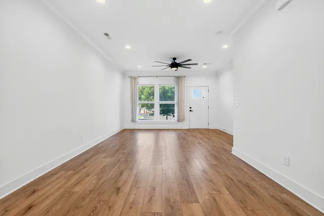 an empty room with wooden floor and windows