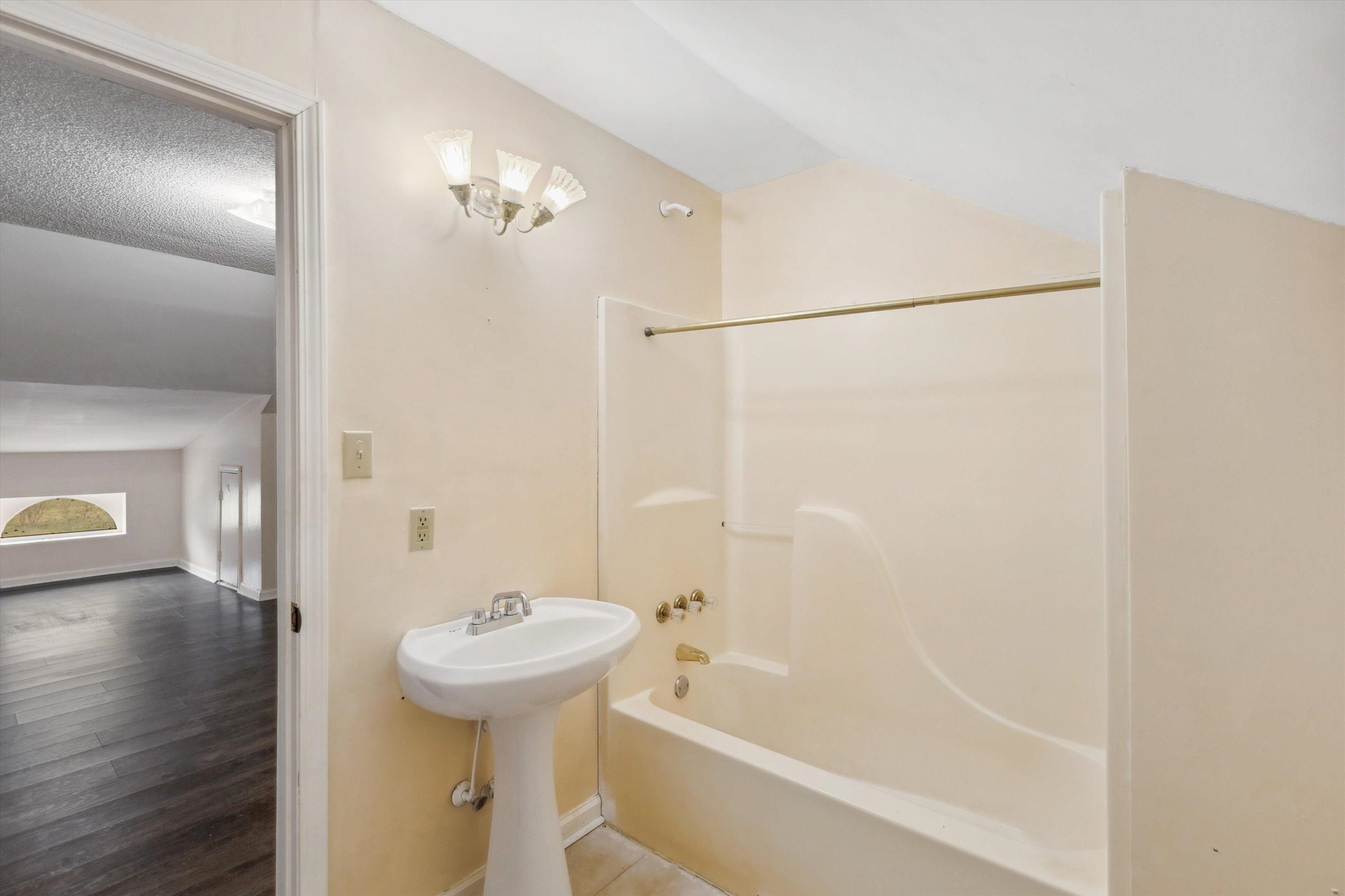 8457 East Kerrville Rosemark Road Millington, TN 38053 - Photo 18 of 25 Bathroom with shower / bathtub combination, wood finished floors, and vaulted ceiling