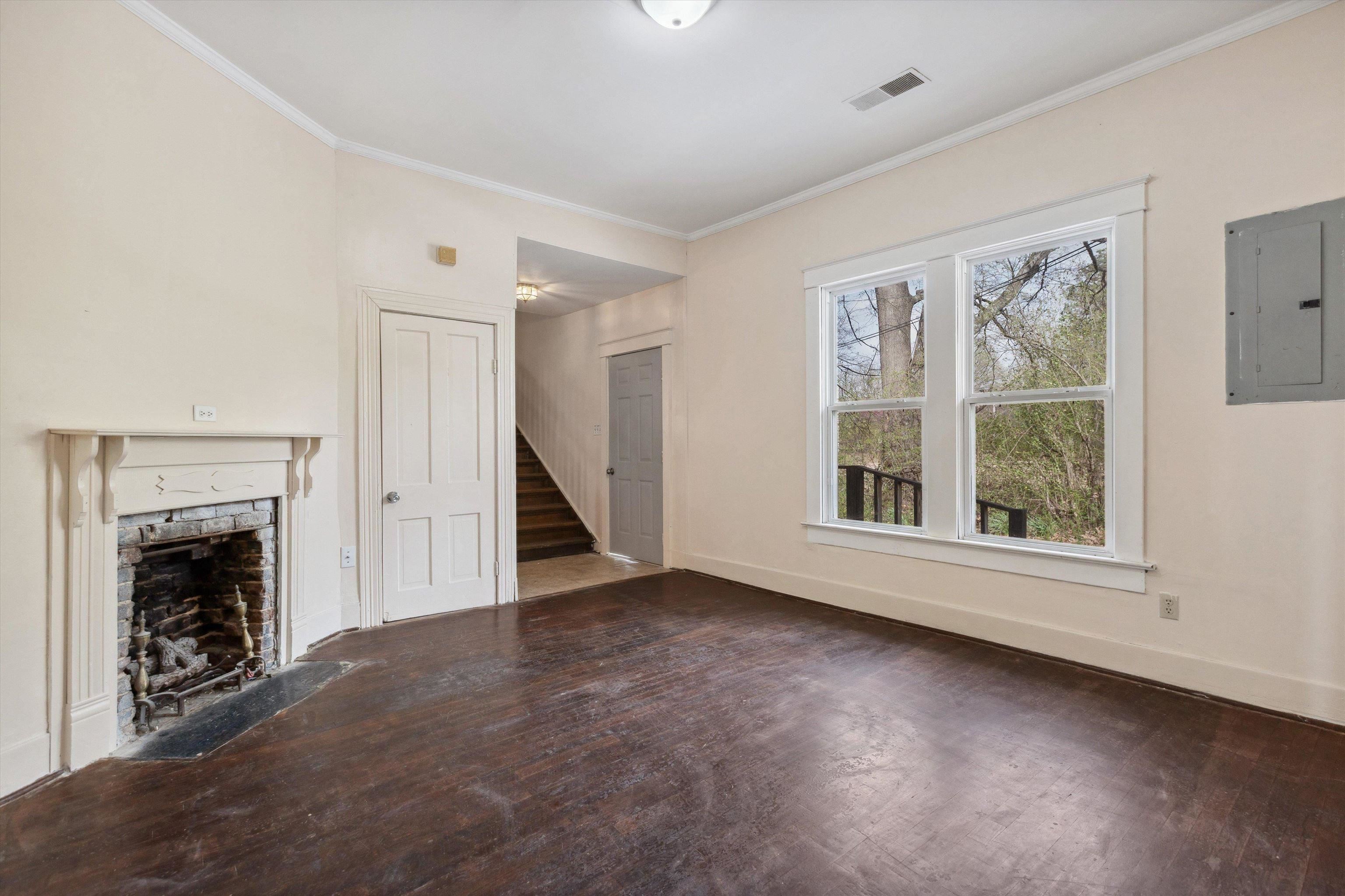 8457 East Kerrville Rosemark Road Millington, TN 38053 - Photo 5 of 25 Unfurnished living room featuring hardwood / wood-style floors, electric panel, ornamental molding, and a fireplace with flush hearth