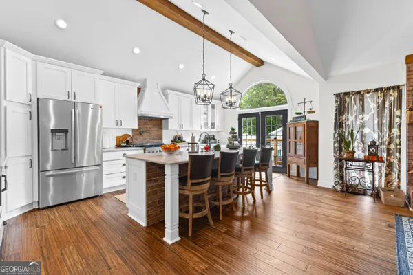 a kitchen with stainless steel appliances kitchen island granite countertop a stove top oven a sink dishwasher and a fireplace with wooden floor