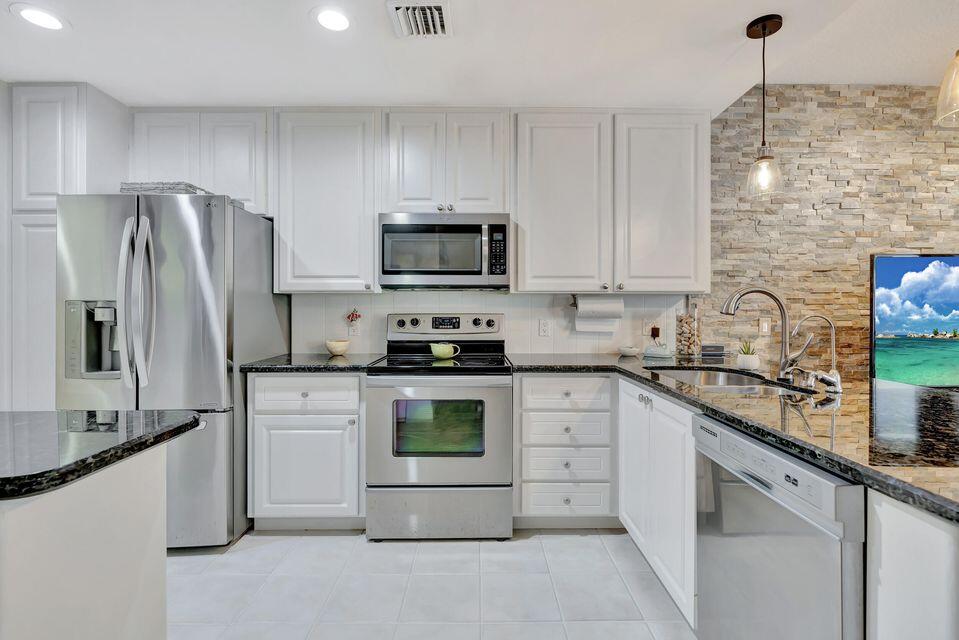 180 Freeport Drive Jupiter, FL 33458 - Photo 22 of 58 a kitchen with granite countertop a refrigerator sink and stainless steel appliances