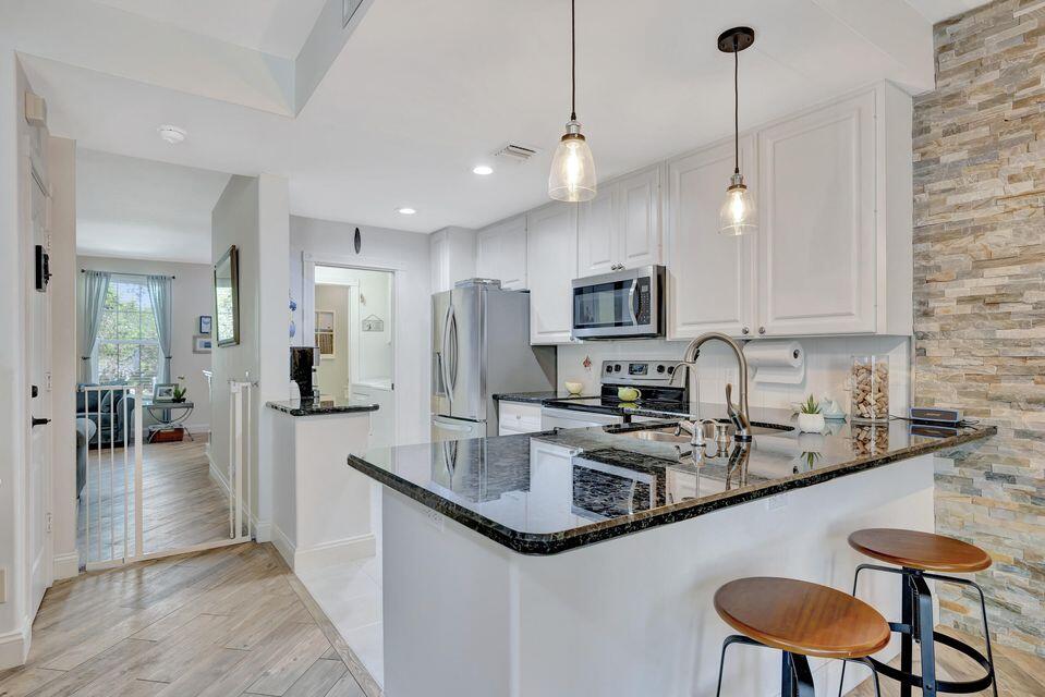 180 Freeport Drive Jupiter, FL 33458 - Photo 23 of 58 a kitchen with stainless steel appliances granite countertop a sink a stove a refrigerator cabinets and chairs