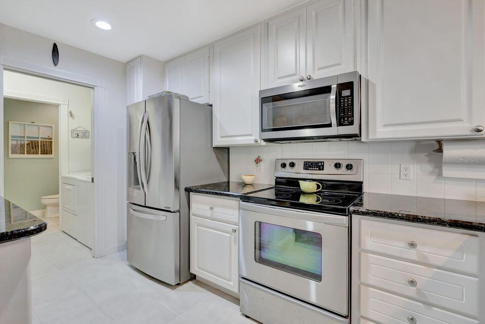 180 Freeport Drive Jupiter, FL 33458 - Photo 24 of 58 a kitchen with granite countertop a refrigerator stove and microwave