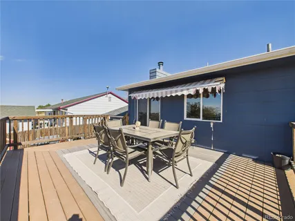 a roof deck with table and chairs under an umbrella with wooden floor
