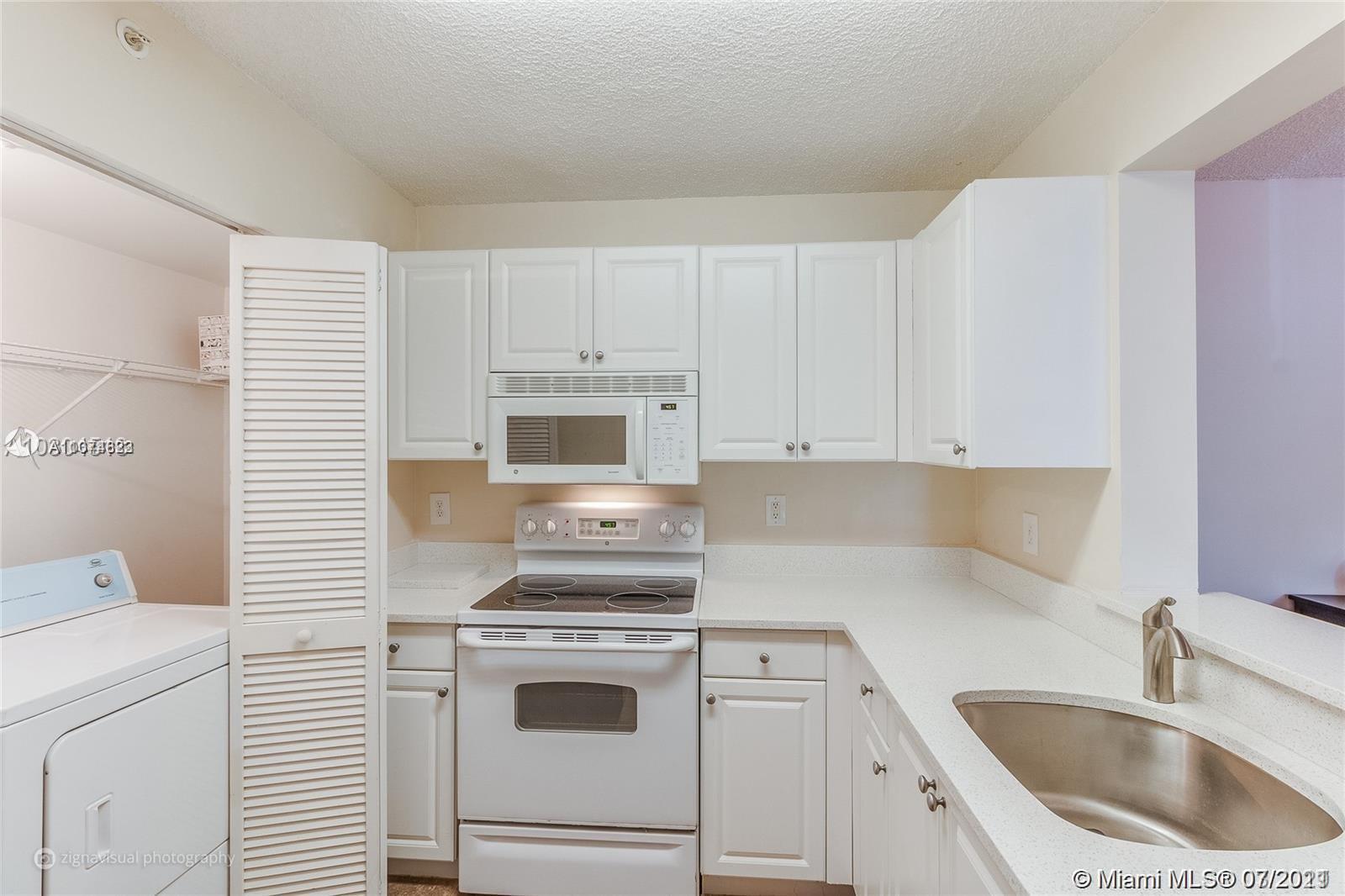 1450 Southeast 3rd Avenue, Unit 107 Dania Beach, FL 33004 - Photo 6 of 15 a kitchen with white cabinets sink and white appliances