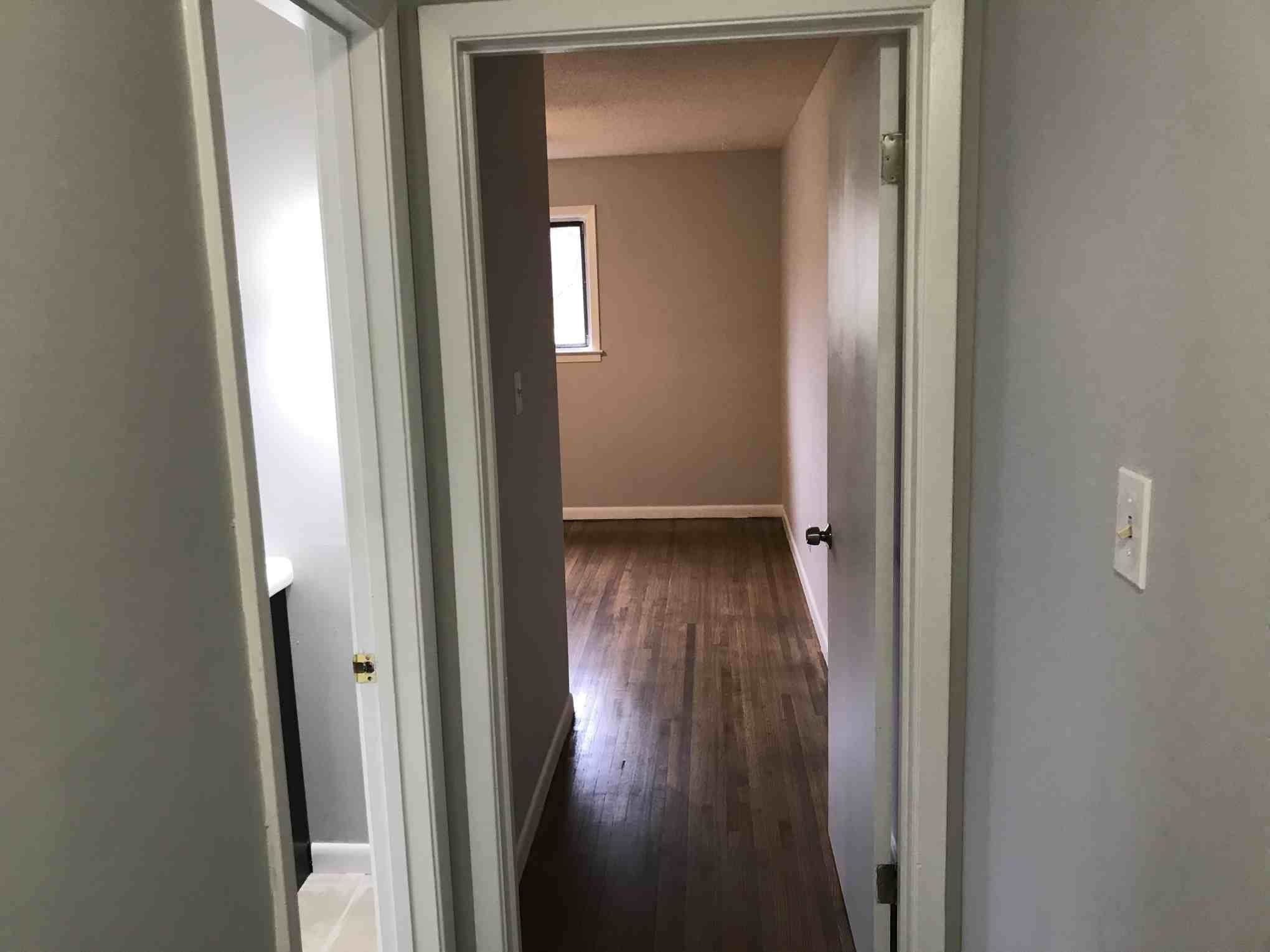 4502 Cottonwood Road Memphis, TN 38118 - Photo 11 of 16 Interior hallway featuring wood-finish flooring, light gray wall paint, white trim, and a white light switch