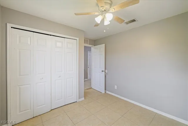 an empty room with a chandelier fan and closet