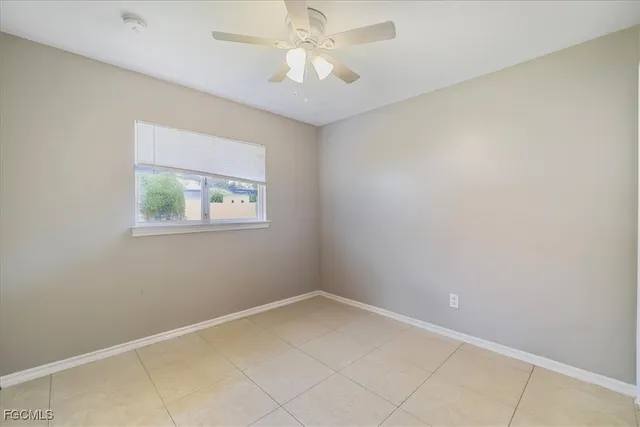 an empty room with a chandelier fan and windows