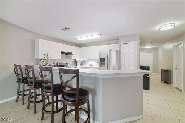 a kitchen with stainless steel appliances a dining table chairs and a refrigerator