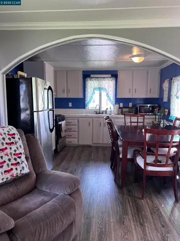 a living room with furniture and a dining table with wooden floor