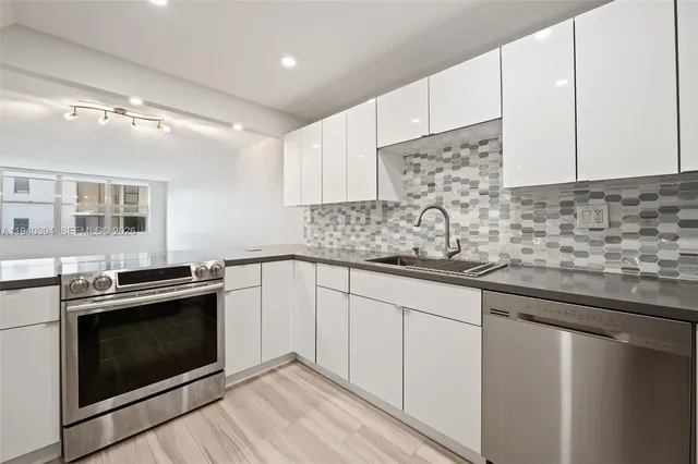a kitchen with stainless steel appliances granite countertop a refrigerator sink and white cabinets