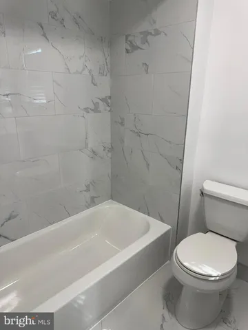 a white toilet sitting next to a bathtub
