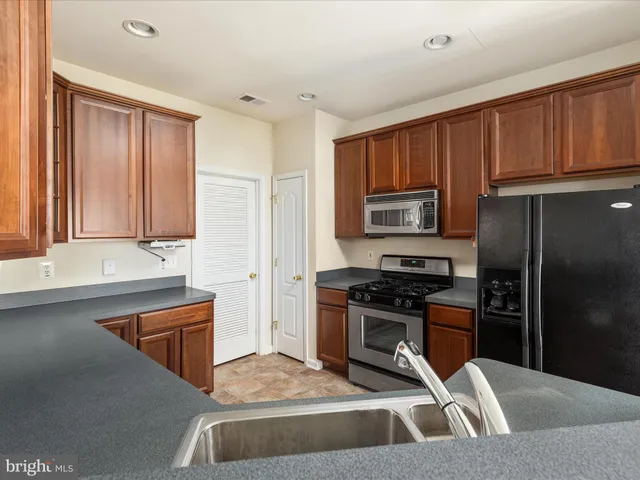 a kitchen with granite countertop a refrigerator stove and sink