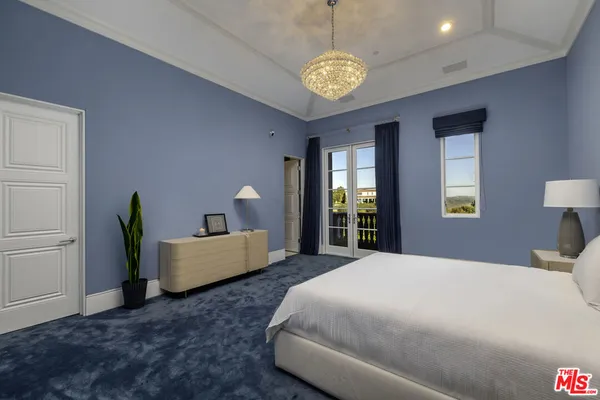 a spacious bedroom with a bed and a chandelier