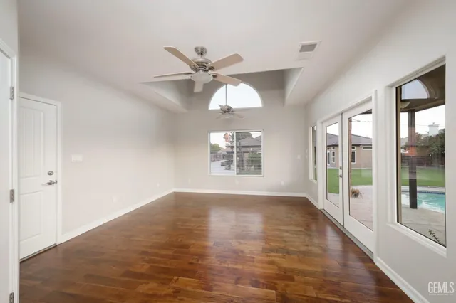 a view of an empty room with window and wooden floor