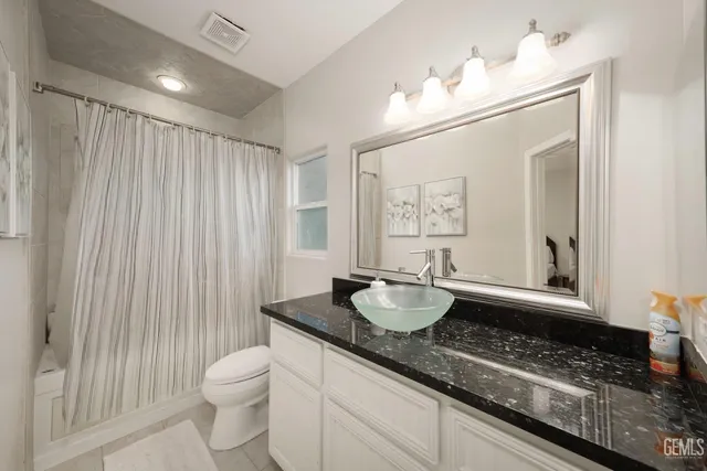 a bathroom with a granite countertop sink a toilet and mirror