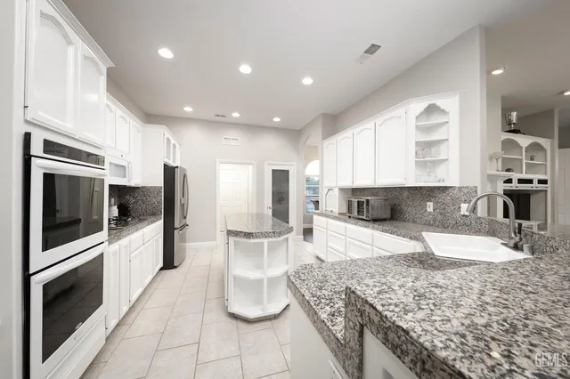 a large kitchen with stainless steel appliances granite countertop a large counter top and a stove top oven