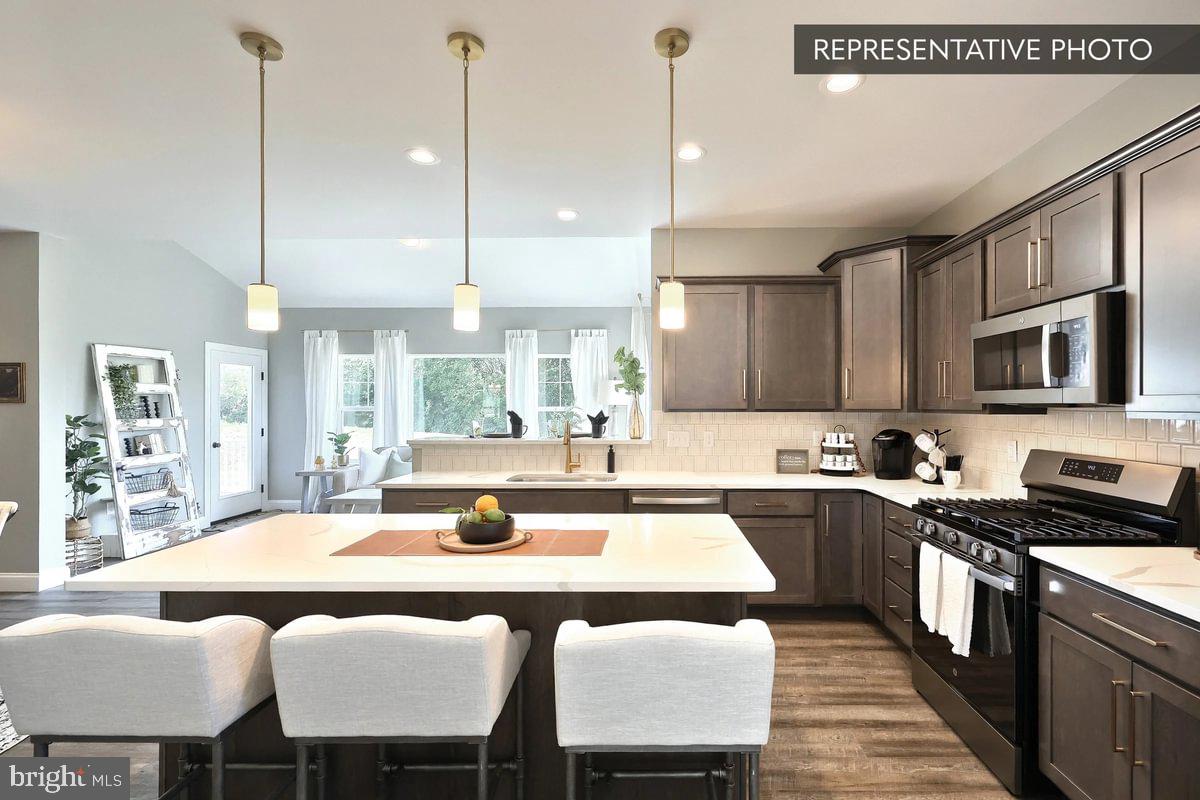Copper Beech Plan At Seiders Hill Pottsville, PA 17901 - Photo 7 of 19 a kitchen with stainless steel appliances granite countertop a sink a stove a dining table chairs and view living room
