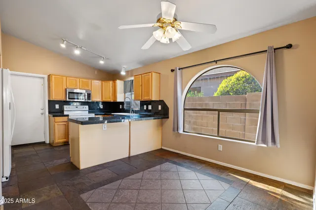 a kitchen with stainless steel appliances granite countertop a refrigerator a stove and a sink with wooden floor