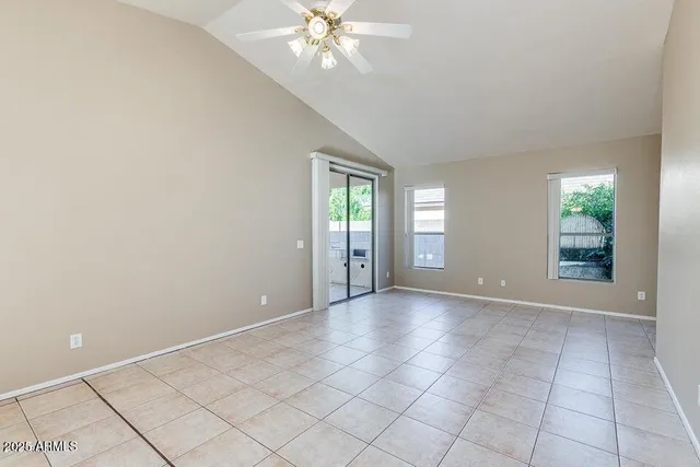 a view of an empty room with window and chandelier fan