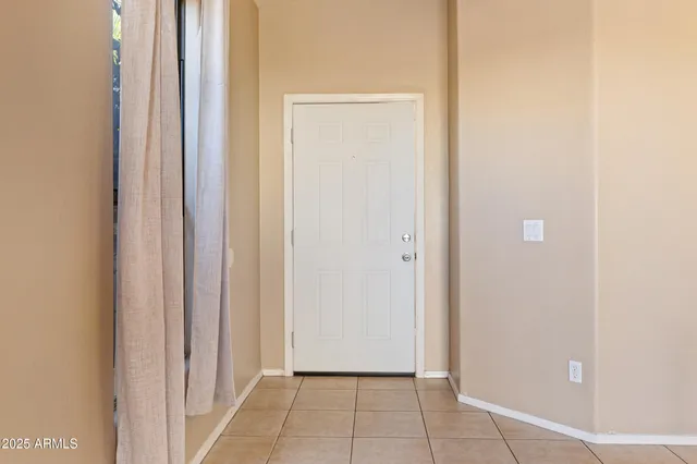an empty room with kitchen and chandelier fan