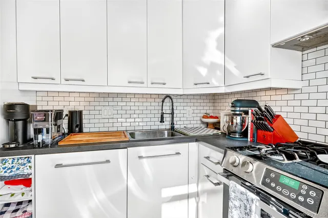 a kitchen with stainless steel appliances a sink a stove and white cabinets