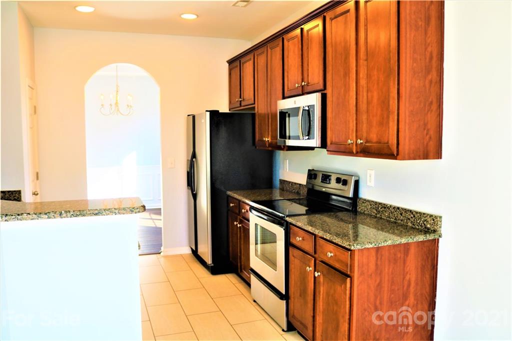 3234 Queensland Court Indian Land, SC 29707 - Photo 2 of 35 a kitchen with stainless steel appliances granite countertop a refrigerator a stove and a sink with wooden cabinets