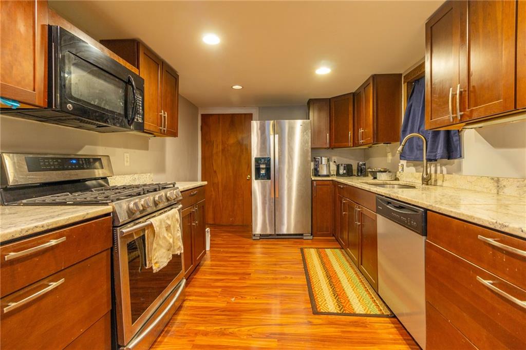 70 South 11th Street Pittsburgh, PA 15203 - Photo 6 of 31 a kitchen with stainless steel appliances granite countertop a sink a stove top oven a refrigerator with wooden floor and cabinets