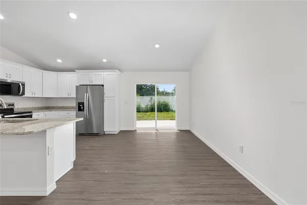 a view of kitchen with stainless steel appliances granite countertop a stove a sink and a refrigerator