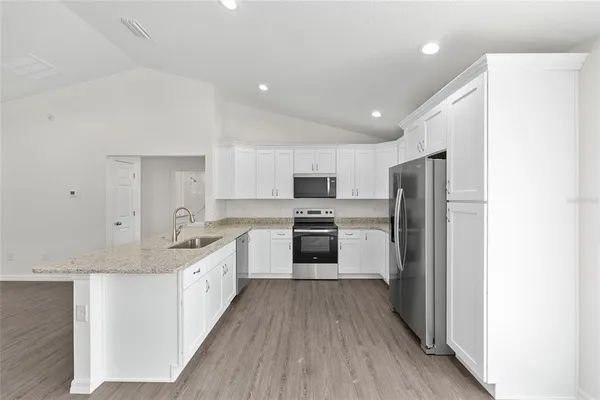 a large kitchen with a center island wooden floor stainless steel appliances and cabinets
