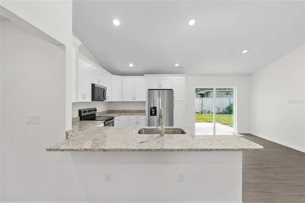 a kitchen with stainless steel appliances granite countertop refrigerator sink and microwave