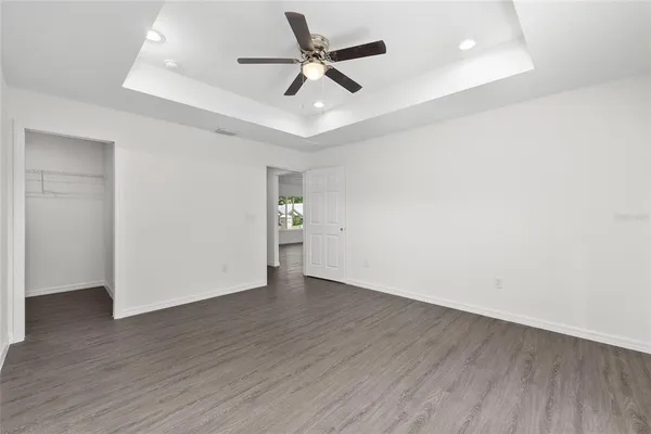 an empty room with wooden floor and ceiling fan