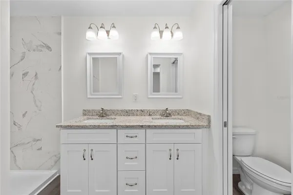 a bathroom with a granite countertop sink toilet and shower