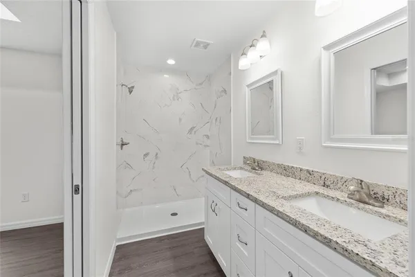 a bathroom with a granite countertop sink mirror and shower