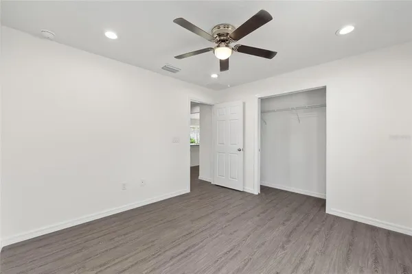 an empty room with wooden floor and a ceiling fan