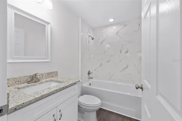 a bathroom with a granite countertop sink a toilet and shower