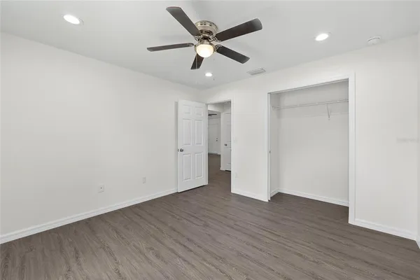 an empty room with wooden floor and ceiling fan