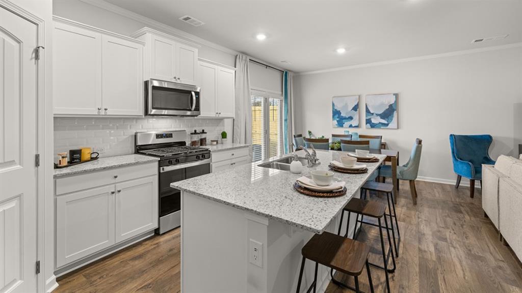 3269 Ryker Road Gainesville, GA 30507 - Photo 6 of 67 a kitchen with stainless steel appliances kitchen island granite countertop a stove a sink a dining table and chairs with wooden floor