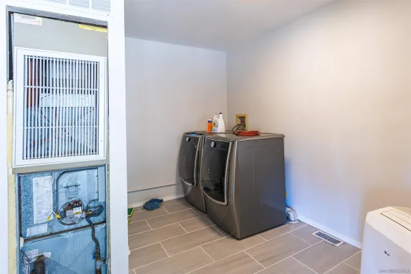 a utility room with stainless steel appliances a refrigerator and a window