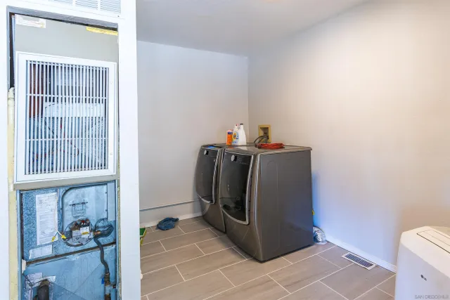 a utility room with stainless steel appliances a refrigerator and a window
