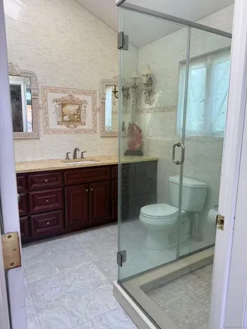 a bathroom with a granite countertop sink toilet a mirror and shower