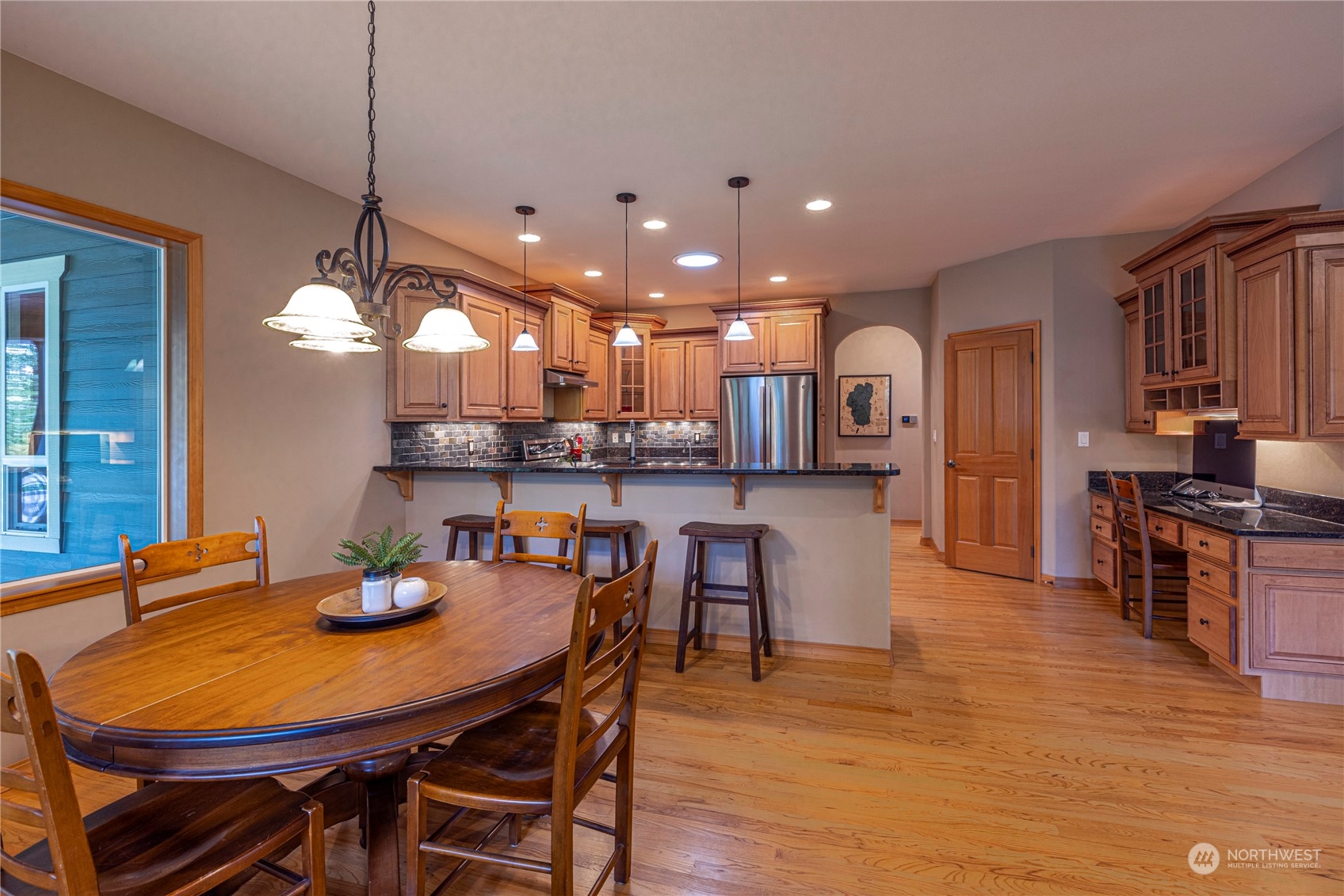 6055 East Hemmi Road Bellingham, WA 98226 - Photo 11 of 40 a kitchen with stainless steel appliances kitchen island granite countertop a dining table chairs and a refrigerator