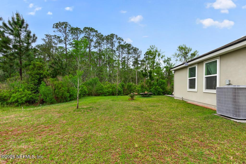 70144 Roseapple Court Yulee, FL 32097 - Photo 26 of 41 a backyard of a house with plants and large tree