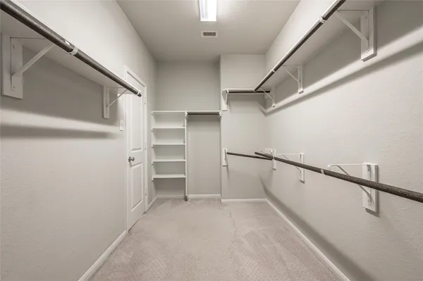 a view of walk in closet with empty racks