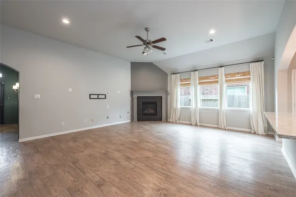 an empty room with chandelier fan and windows
